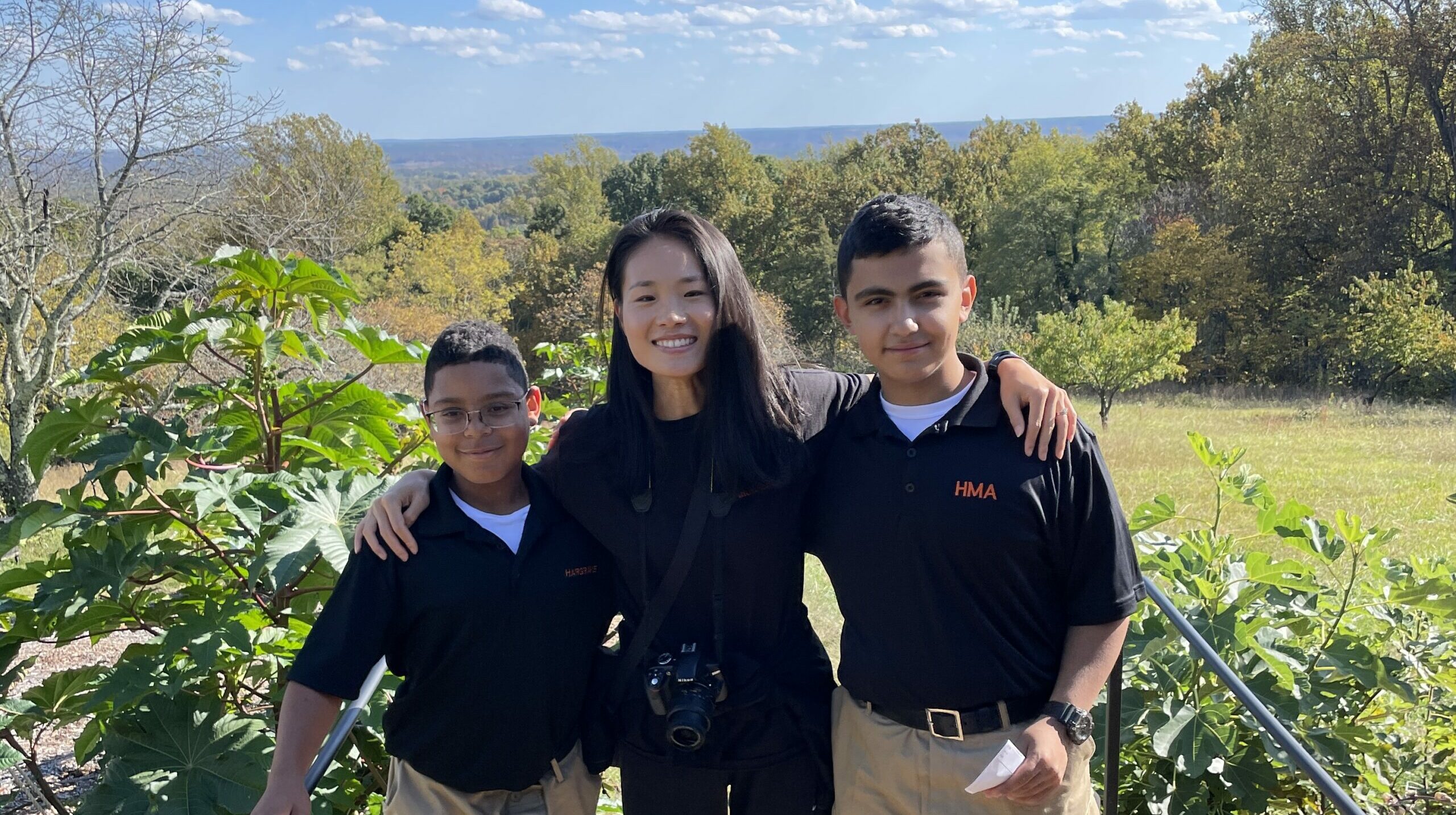 Two international cadets posing on either side of their teacher facing the viewer.