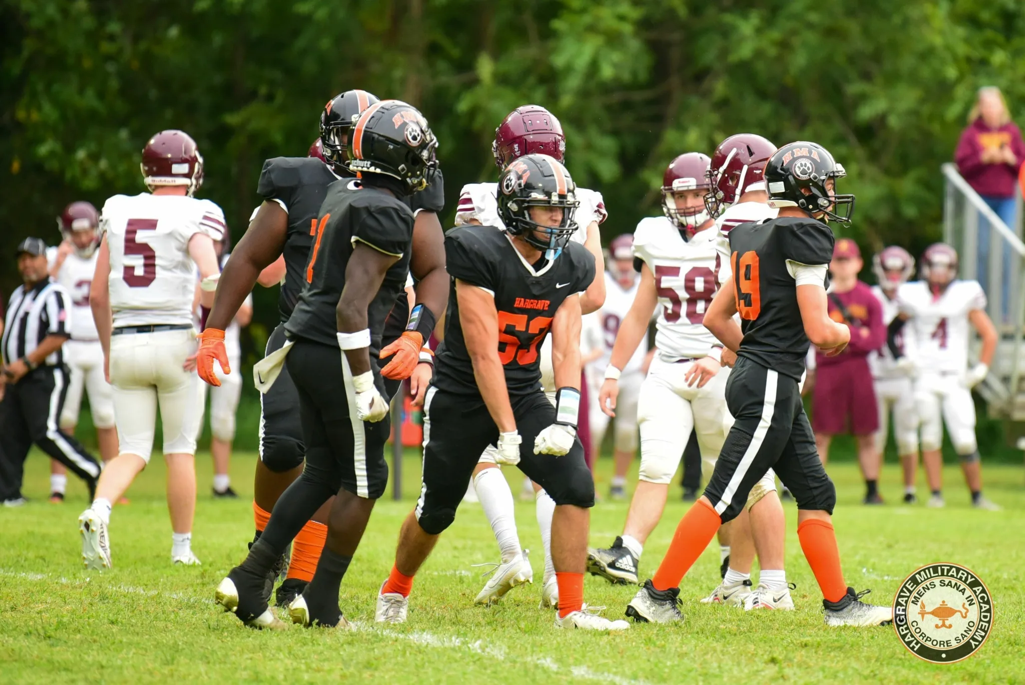 Hargrave football players at the line of scrimmage in black and orange