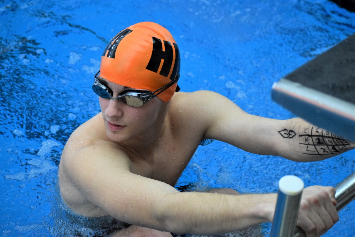 Member of swim team on starting block in pool.